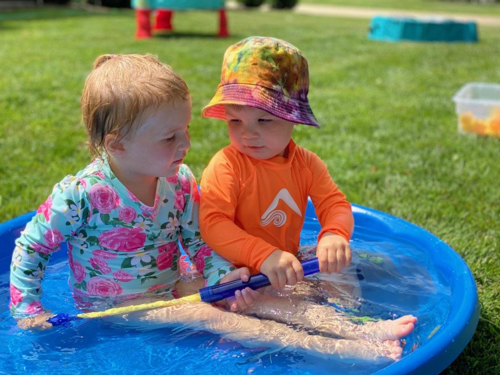 Two children playing in a pool of water together.