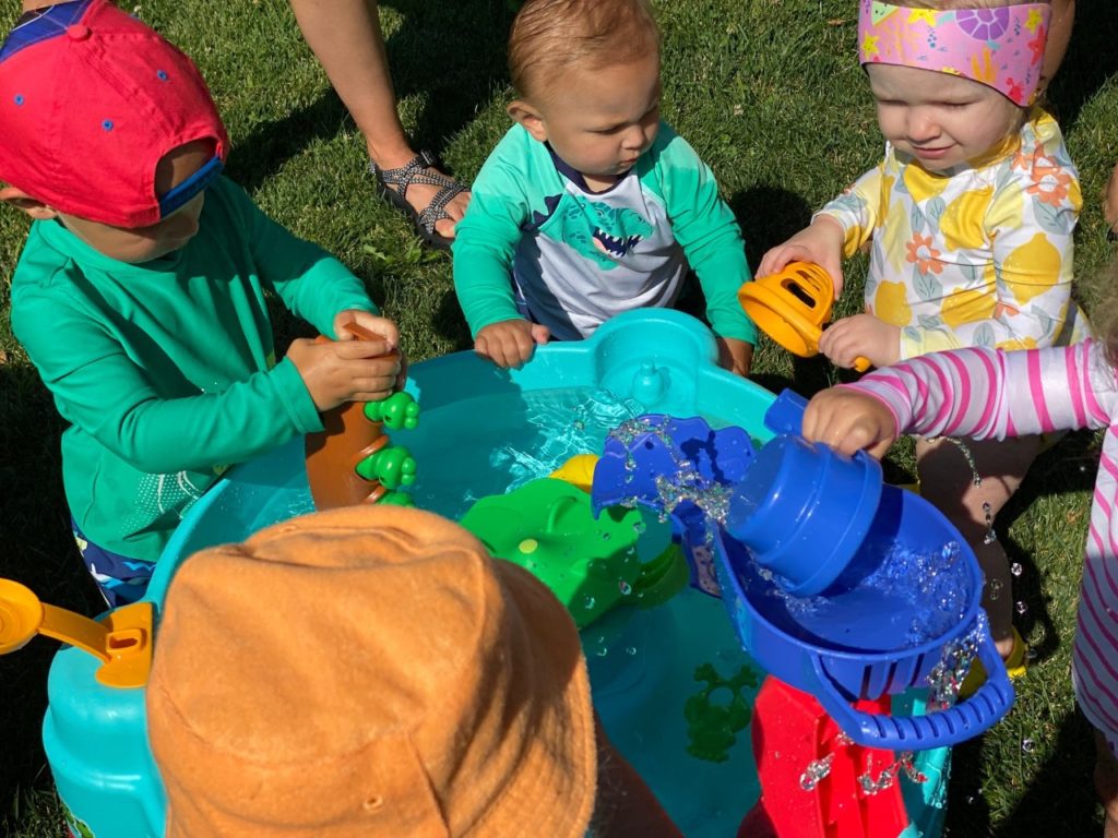 Four children playing together at a water table designed for little ones.
