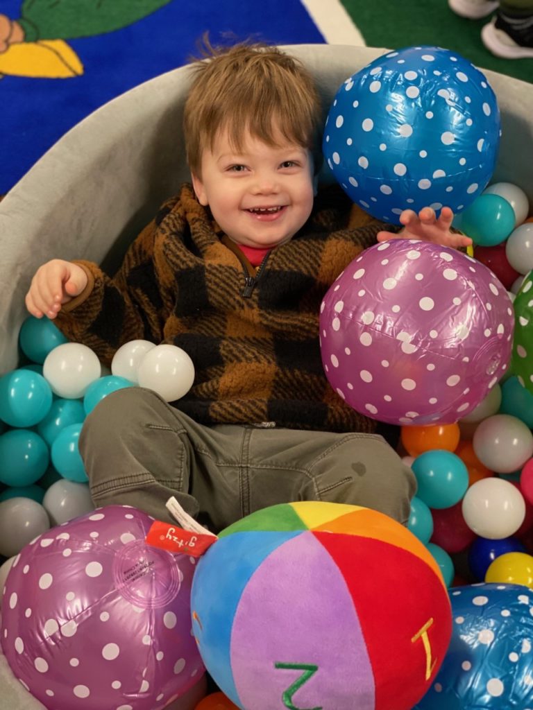 Child playing in ball pit during story time.